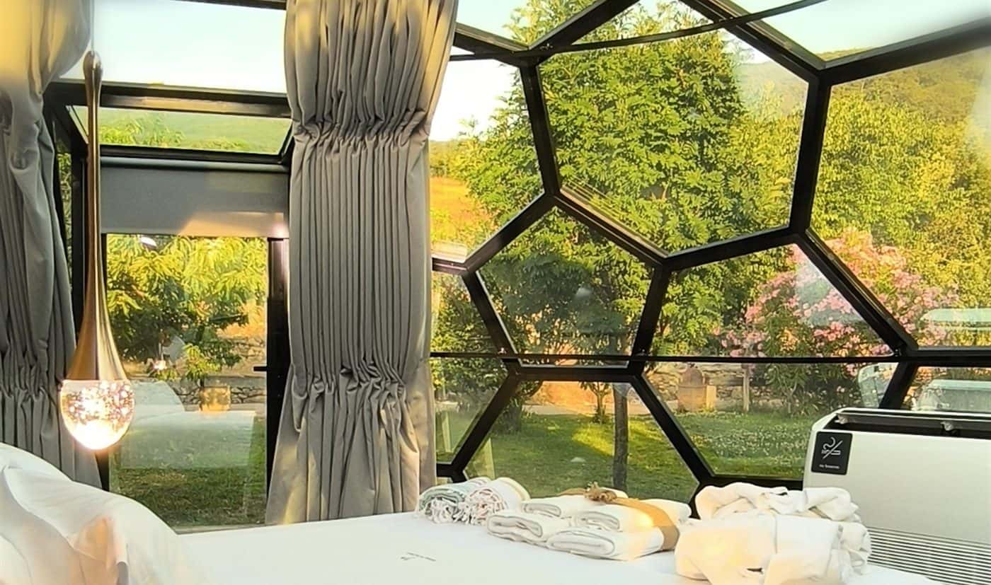 Interior de un domo con la cama preparada y el valle al otro lado del cristal